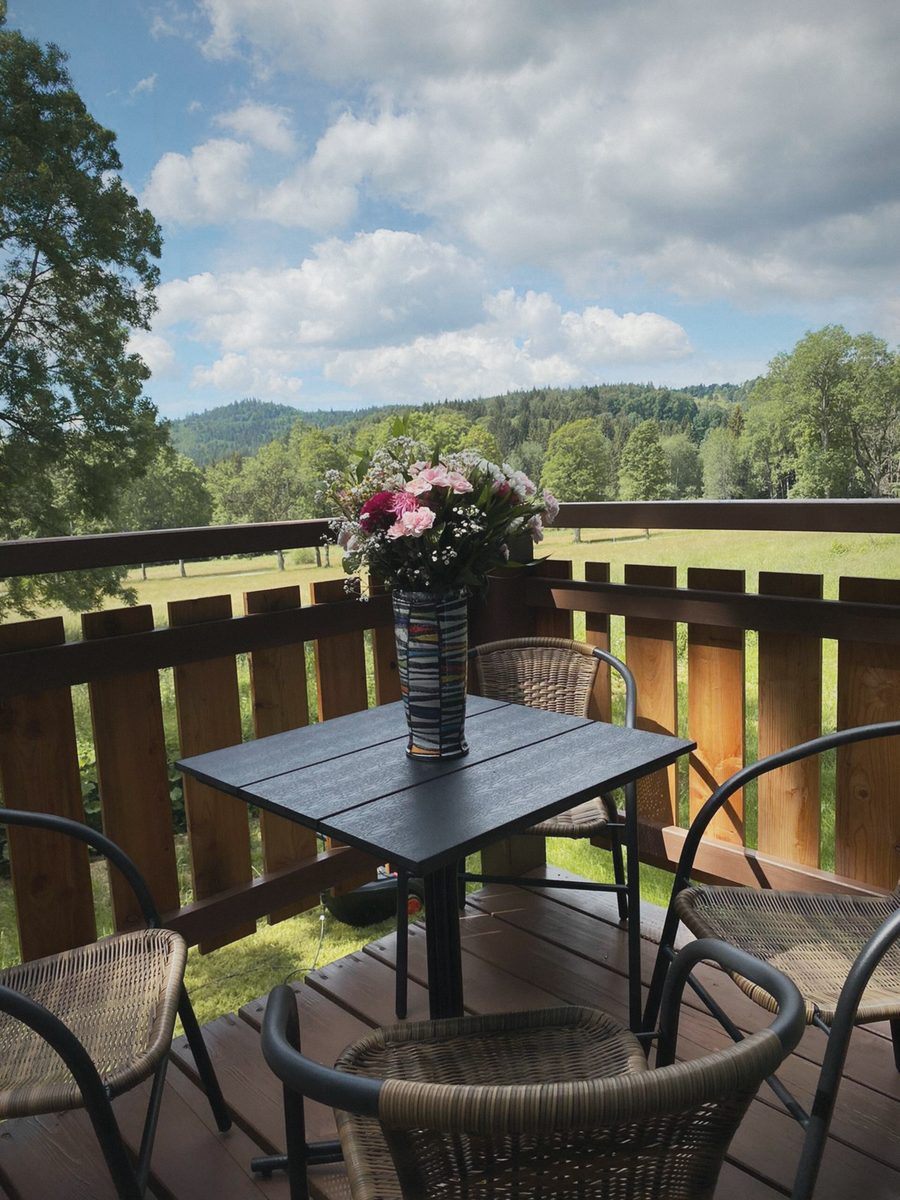 Balkon s květinami a výhledem na kopce