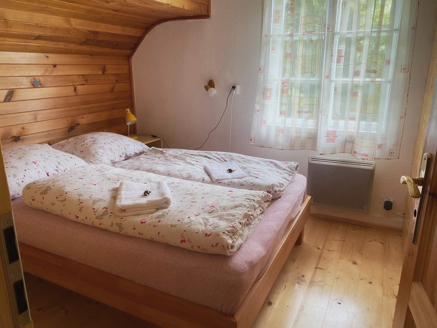 Podkrovní pokoj s dřevěným obložením, postele u okna